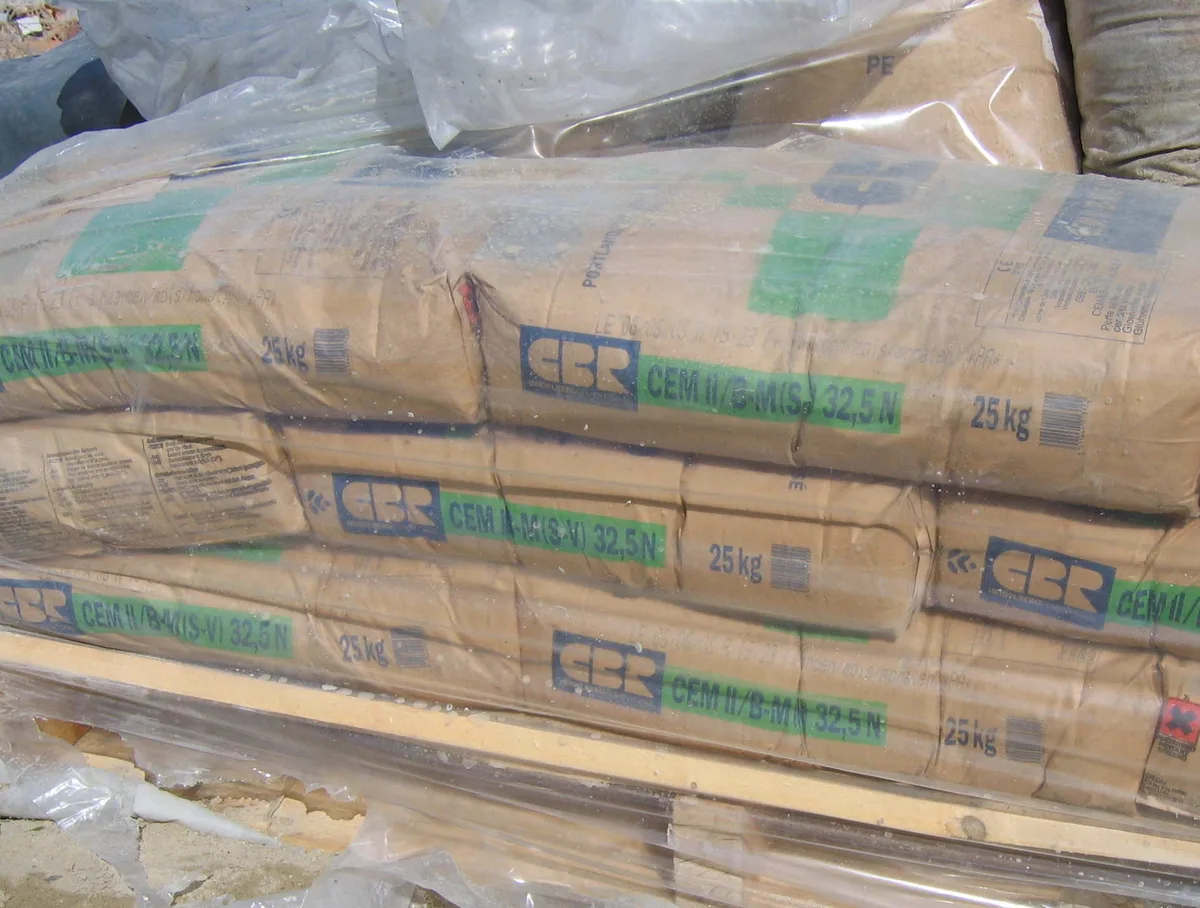 Stacked 25 kg bags of CBR CEM II/B-M 32,5 N Portland cement shrink-wrapped on a wooden pallet