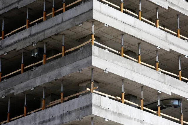 Corner of a multi-storey concrete frame under construction with slab edges and timber safety rails