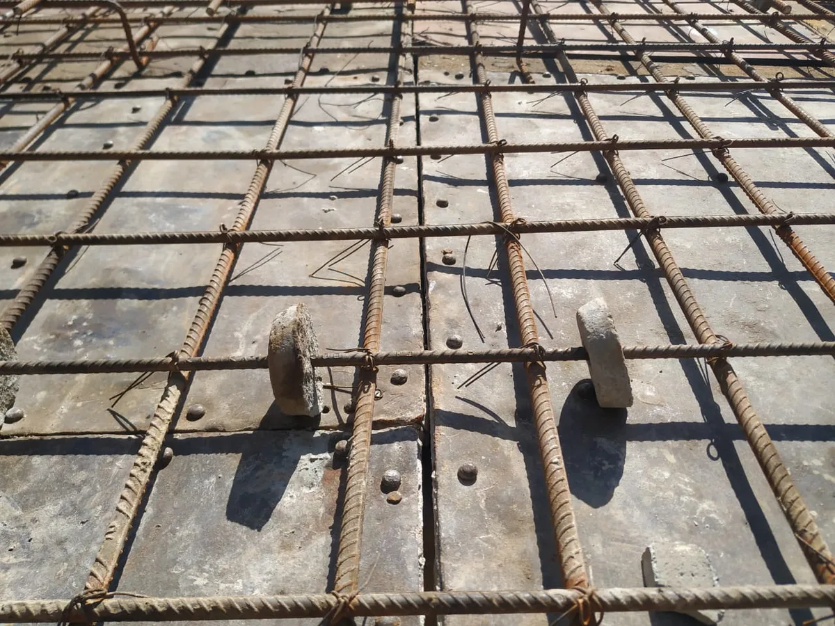 Two round concrete cover blocks supporting a slab rebar mesh above steel shuttering plates