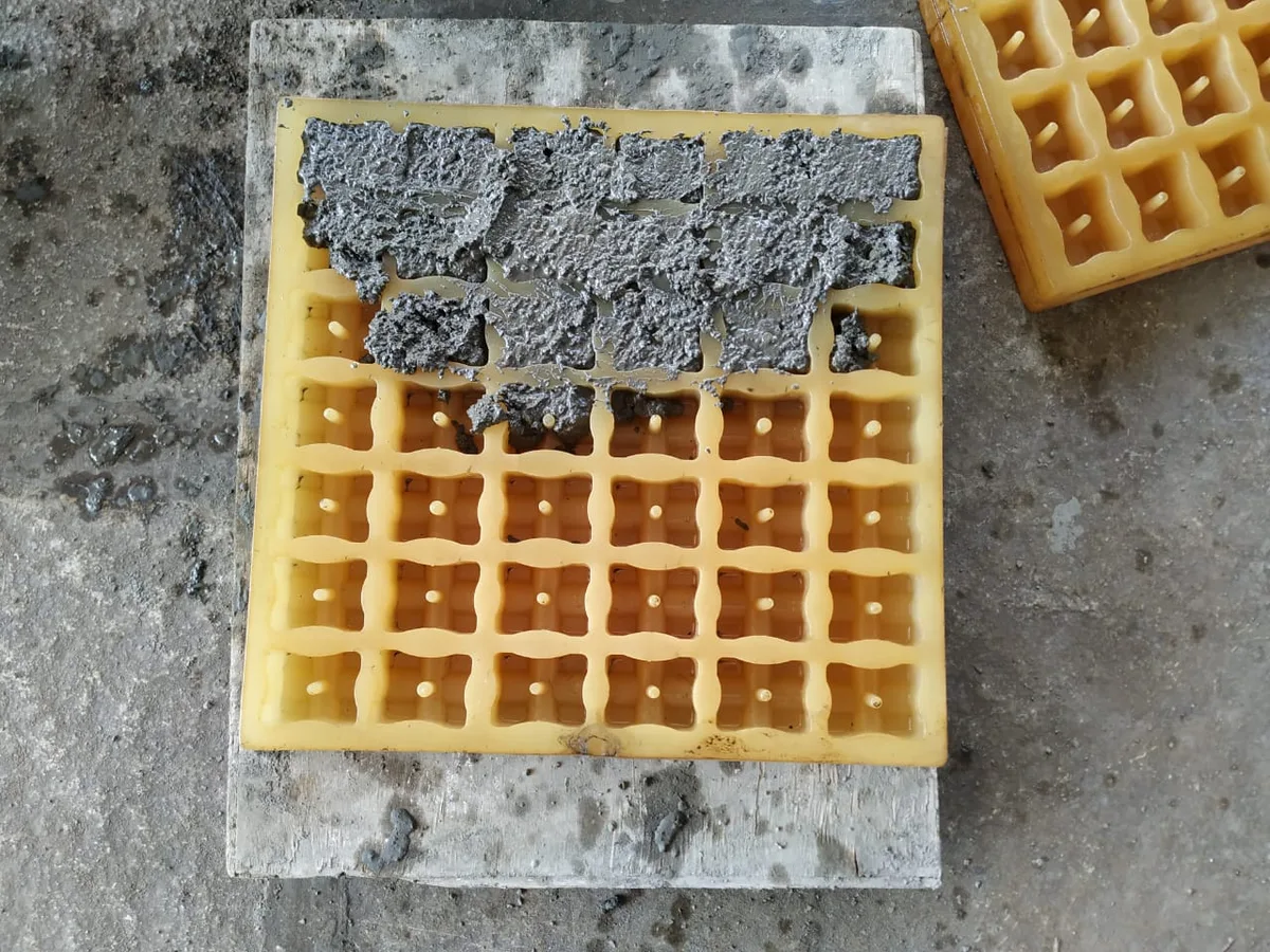 Yellow multi-cell cover block mould on a board, partly filled with fresh mortar