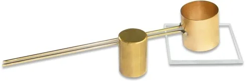 Brass Le-Chatelier mould with two long indicator rods beside a taller brass cylinder on a square glass plate