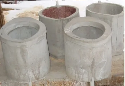 Four hollow grey concrete cylinders with thick walls standing on posts in snow