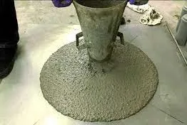 Slump cone being lifted over a very flowable concrete that has spread into a flat disc on the floor