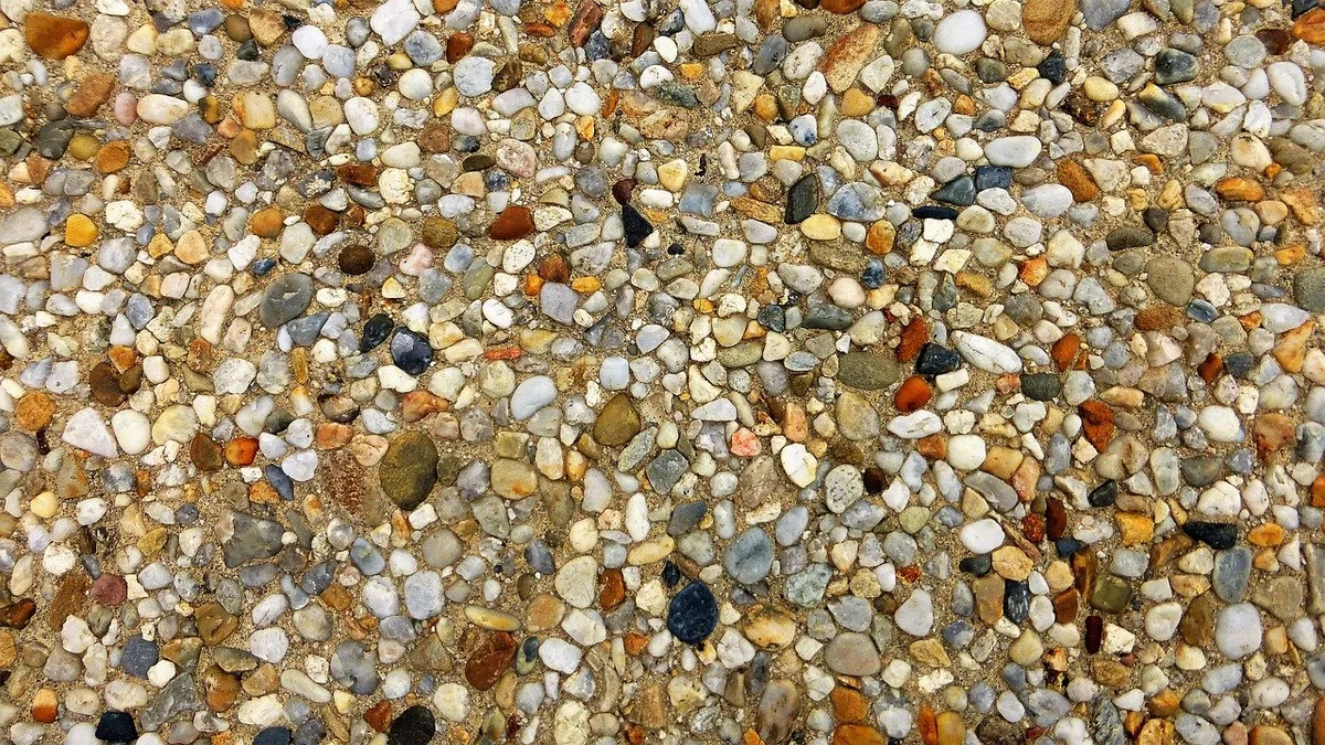 Rounded multicoloured gravel pebbles packed in sand, seen from above