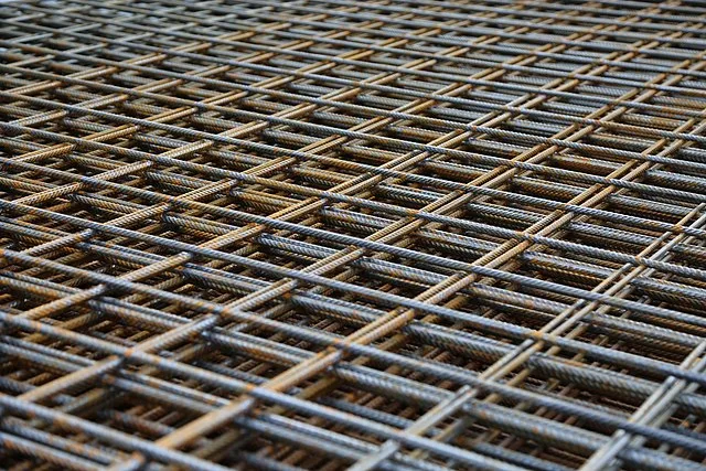 Stacked grids of deformed steel rebar mesh, some bars lightly rusted